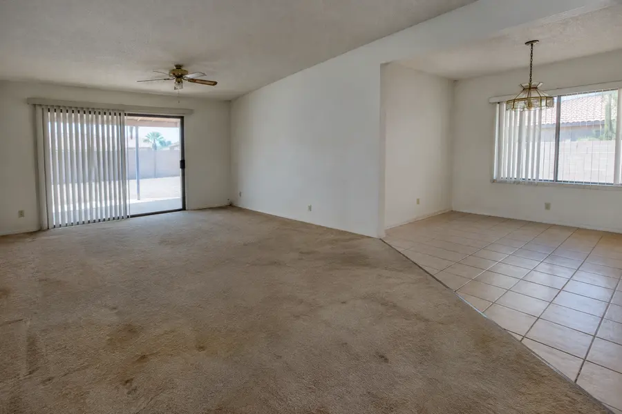 Dated living and dining area with worn carpet and old ceramic tile