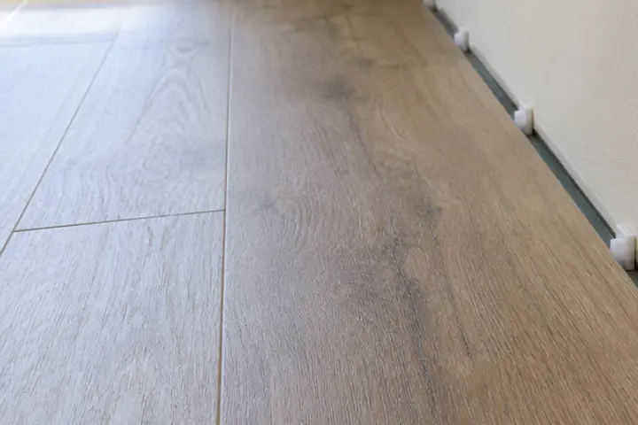 Expansion gap with spacers between a new plank floor and the wall